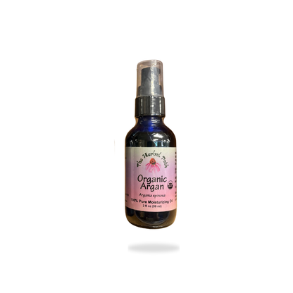 Bottle of organic argan oil with a pink label by The Herbal Path on a white background.