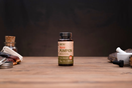A bottle of ORKS Organic Pumpkin Seed Oil centered on a wooden tabletop with a dark, moody background. The amber glass bottle has a black cap and a tan label with green and orange text.