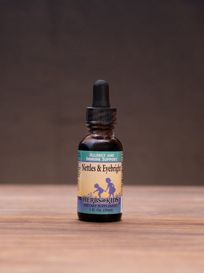 A small amber glass dropper bottle with a cream label stands centered on a wooden tabletop against a dark brown backdrop. The label reads 'Saffron & Turmeric' with a blue horse illustration.