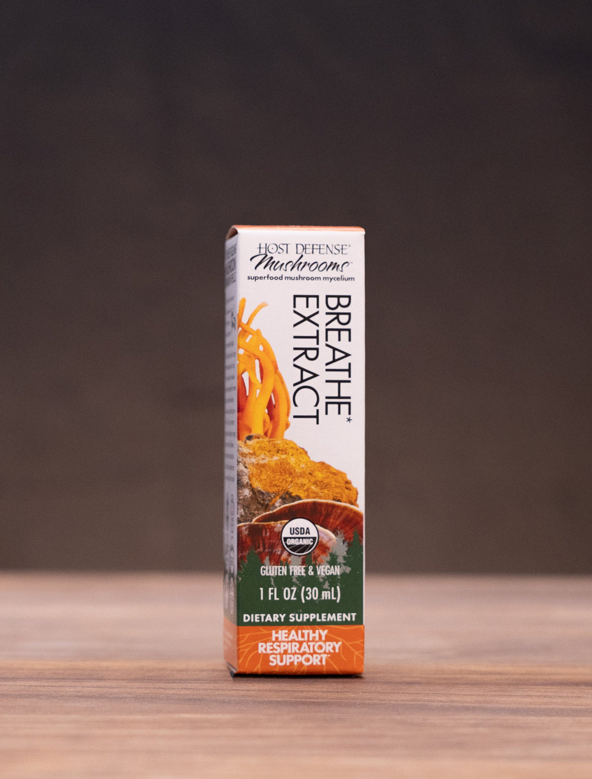 A box of Bruges Organic Decaffeinated Coffee centered on a wooden tabletop with a dark, moody background and rustic props on both sides.