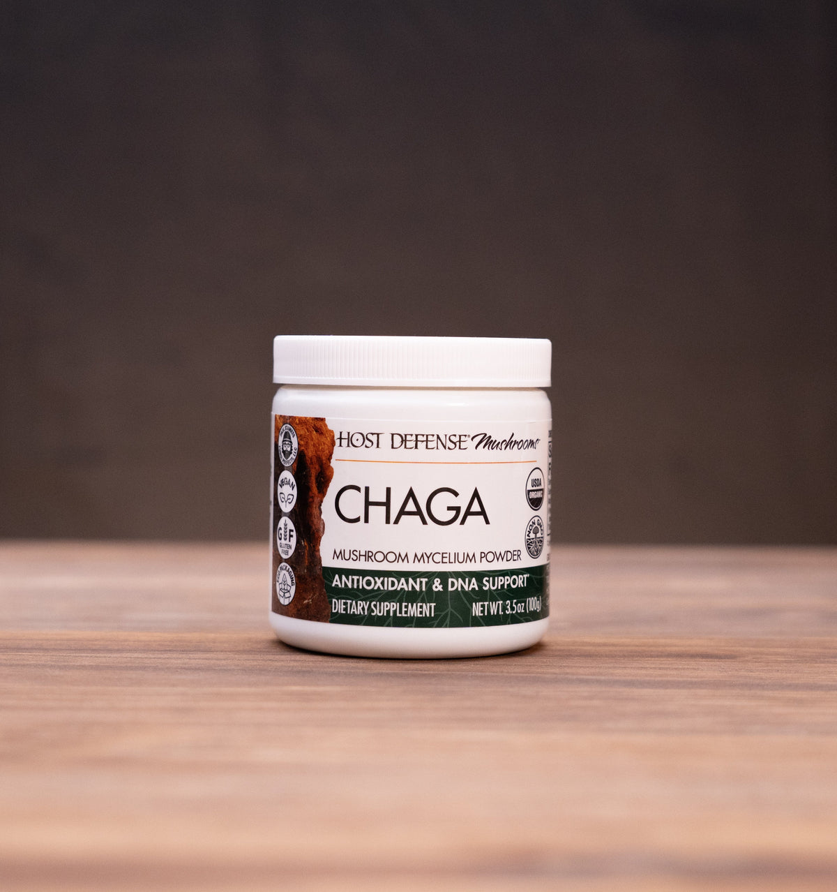 A jar of Chaga Antioxidant & Zinc Supplement by Root Defense Products, set on a rustic wooden table with mystical props in the background.