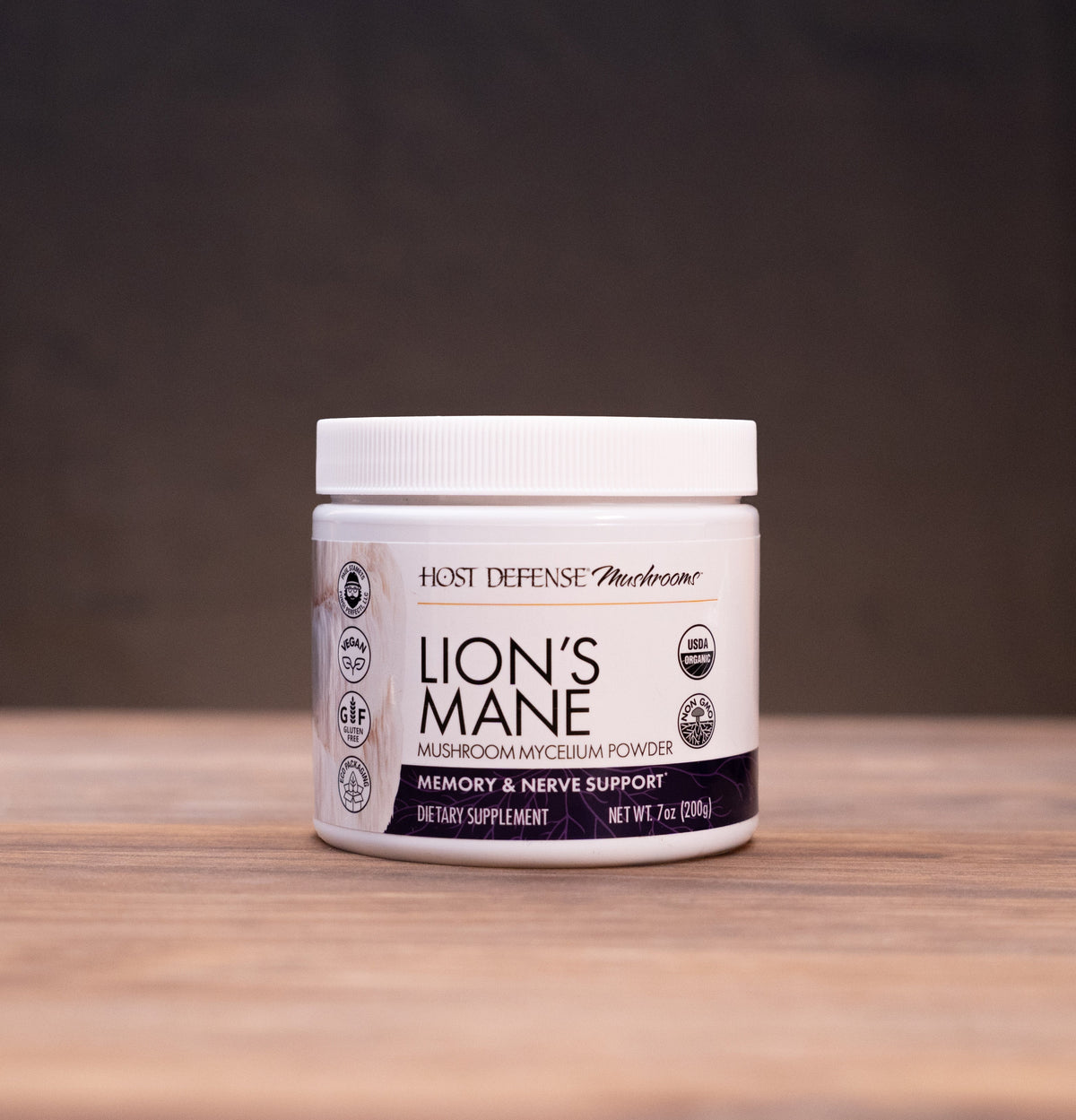 A white jar of Haze Defense 'Blossom' Lion's Mane supplement sits on a rustic wooden table, flanked by herbal ingredients and a mortar and pestle in the background.