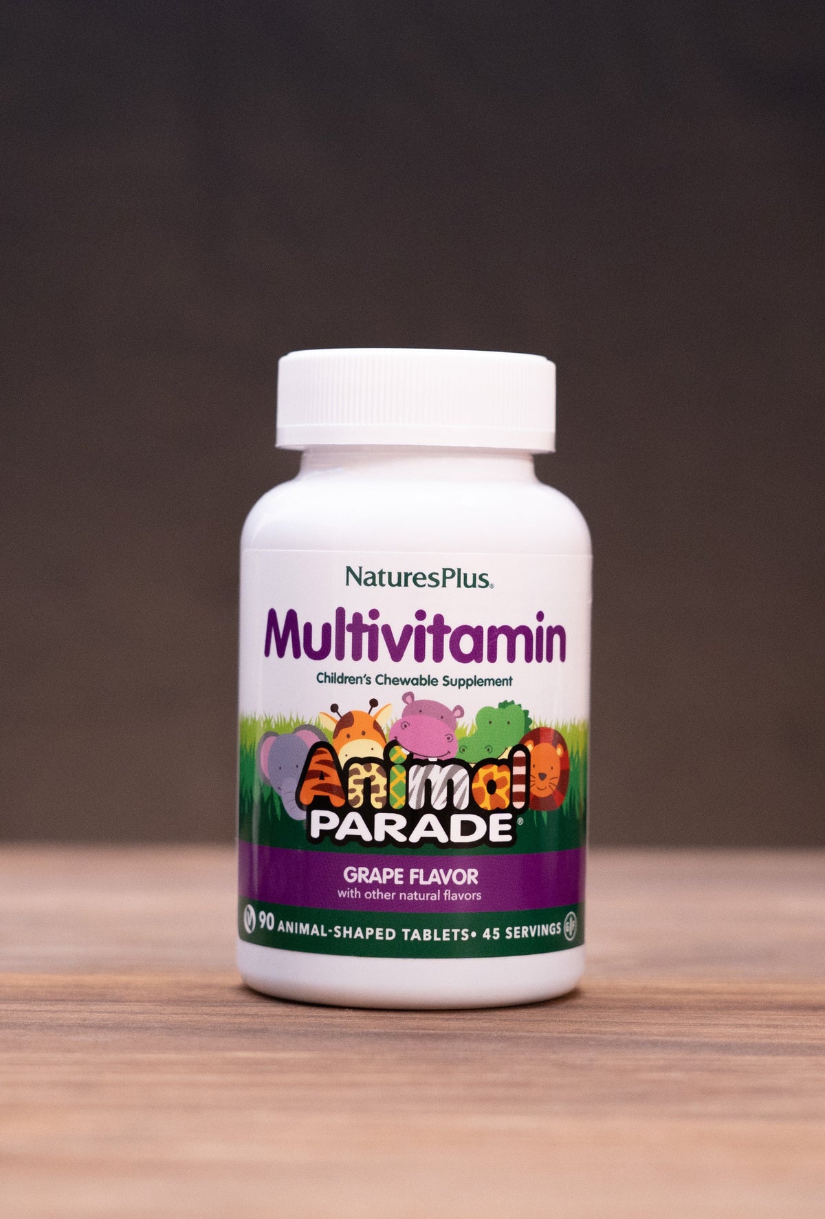 A bottle of Nature's Plus Multivitamin in Grain Flavor, set on a rustic wooden table with natural props like a cork stopper, dried herbs, and a mortar and pestle against a dark background.