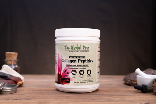 A white plastic jar of 'The Herbal Path' Collagen Peptides centered on a rustic wooden table, surrounded by herbal props like a mortar and pestle, dried roots, and a small glass vial against a dark backdrop.