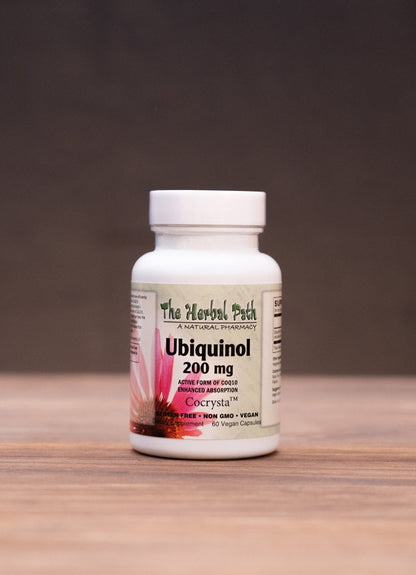 A white bottle of The Medicine Patch GeEnzyme Q10 Softgel 300 mg stands centered on a wooden tabletop against a dark background, with blurred herbal props on both sides.