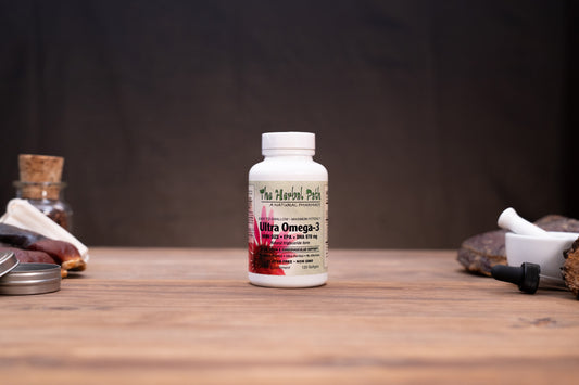 A white bottle of The Harvest Pond Ultra Omega-3 dietary supplement stands on a wooden tabletop against a dark, blurred background. The bottle is flanked by rustic props, including a cork stopper, a small glass jar, and a white mortar and pestle.