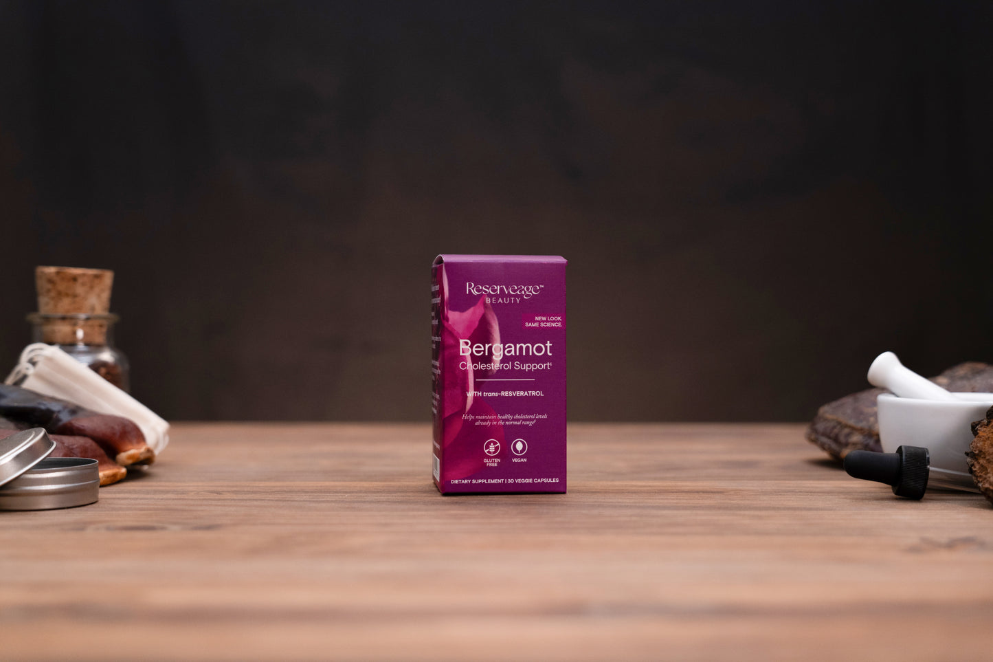 A box of Berberine Gummies by Resurgence on a wooden tabletop, flanked by apothecary props like a glass bottle and mortar and pestle against a dark background.