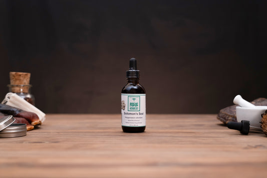 A small amber glass dropper bottle labeled Focus & Balance Skin Care by The Apothecary's Shop, set on a wooden tabletop with rustic props in the background.