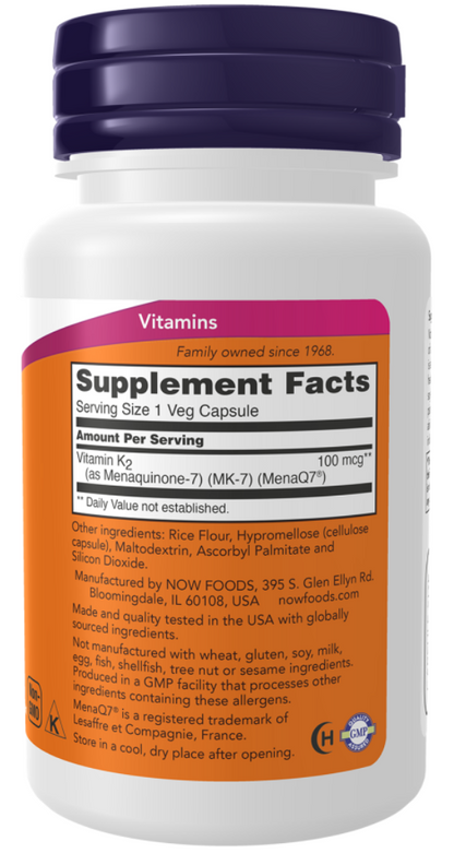 A white plastic bottle of NOW Foods Vitamins with a dark purple cap and an orange and white supplement facts label.