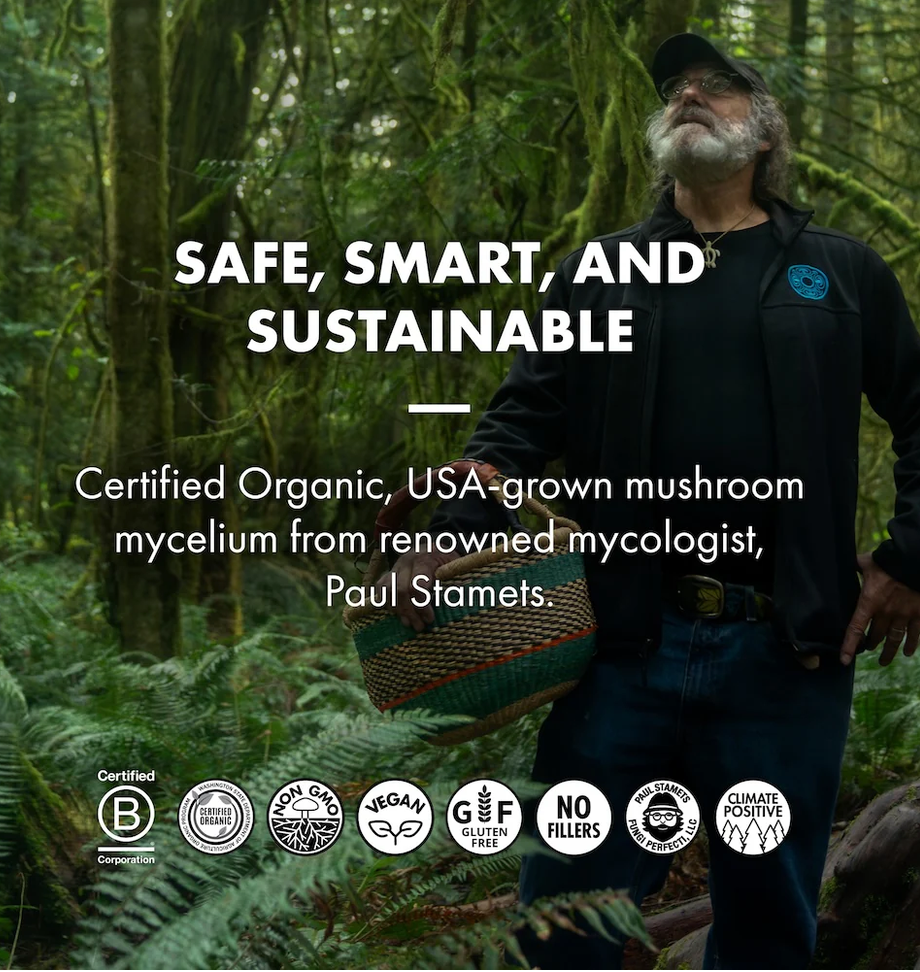 A man wearing a black cap, black jacket, and blue jeans stands in a lush green forest while holding a woven basket. Large white text reads 'SAFE, SMART, AND SUSTAINABLE' with supporting text about certified organic mushroom mycelium from mycologist Paul Stamets.