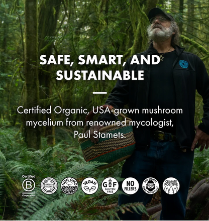 A man wearing a black cap, black jacket, and blue jeans stands in a lush green forest while holding a woven basket. Large white text reads 'SAFE, SMART, AND SUSTAINABLE' with supporting text about certified organic mushroom mycelium from mycologist Paul Stamets.