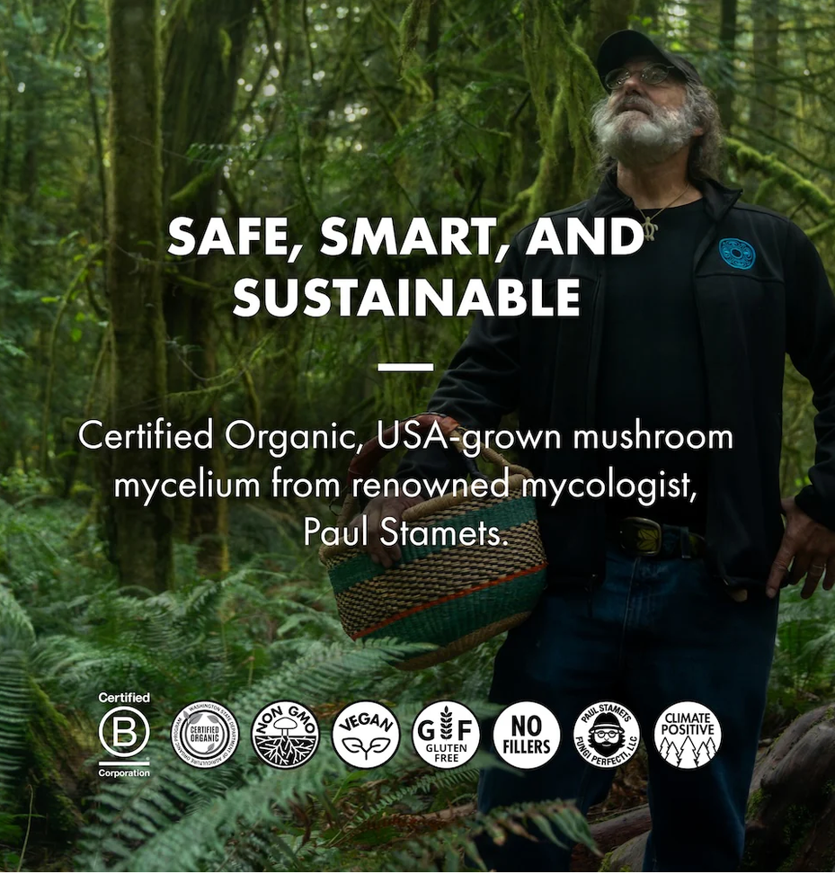 A man wearing a black cap, black jacket, and blue jeans stands in a lush green forest while holding a woven basket. Large white text reads 'SAFE, SMART, AND SUSTAINABLE' with supporting text about certified organic mushroom mycelium from mycologist Paul Stamets.