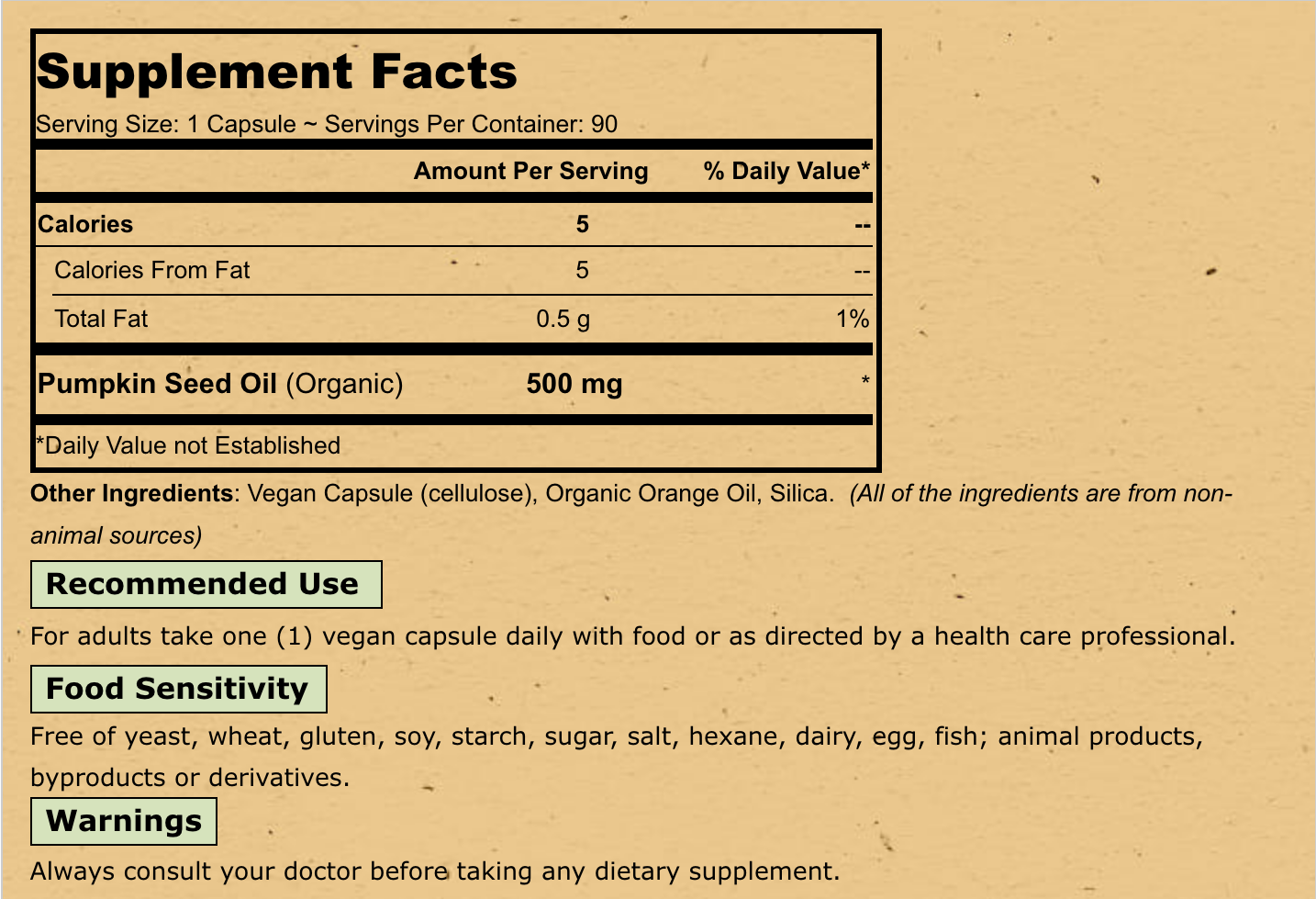 A close-up of a supplement facts label on a beige package, showing text for Pumpkin Seed Oil (Organic) 500 mg, including serving size, calories, daily value, recommended use, food sensitivity, warnings, and disclaimer.