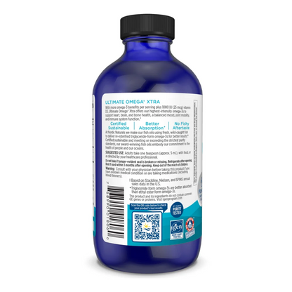 A blue bottle of Ultimate Omega Xtra fish oil supplement shown from the back, featuring a black cap and a white and teal label with text and QR codes.