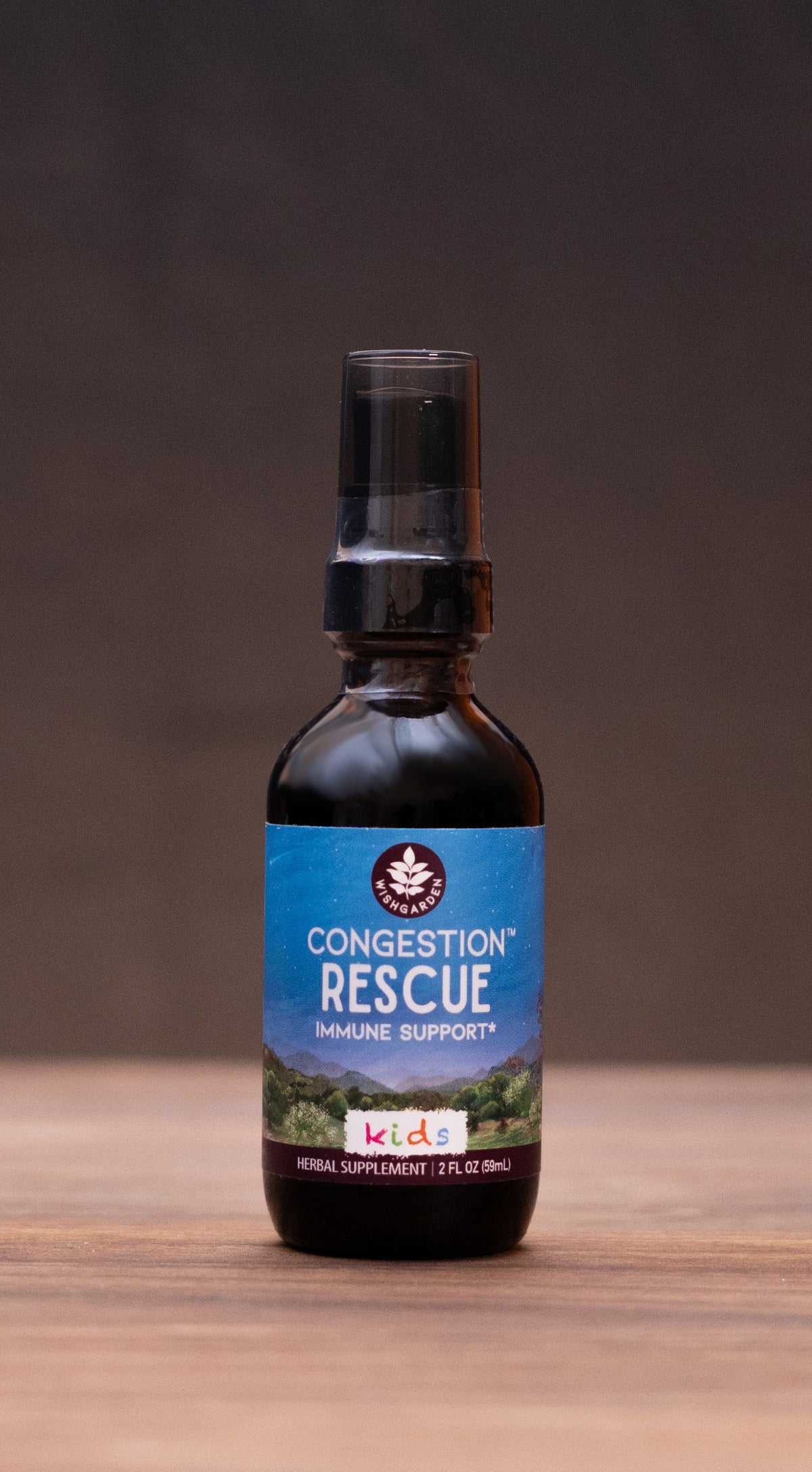 A small amber glass bottle labeled 'Concentrate Rescue' stands centered on a wooden tabletop against a dark backdrop, with blurred rustic props on both sides.