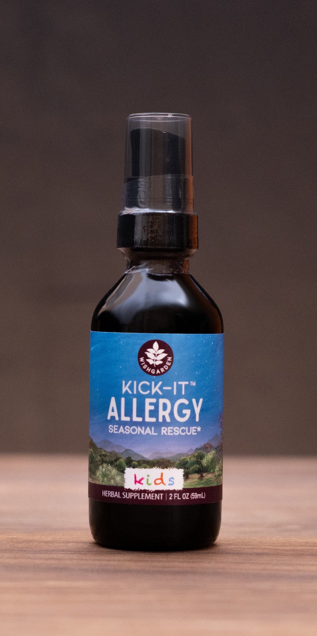 A small amber bottle labeled 'Natural Allergy Relief' stands centered on a wooden tabletop against a dark backdrop, with blurred natural props visible on both sides.